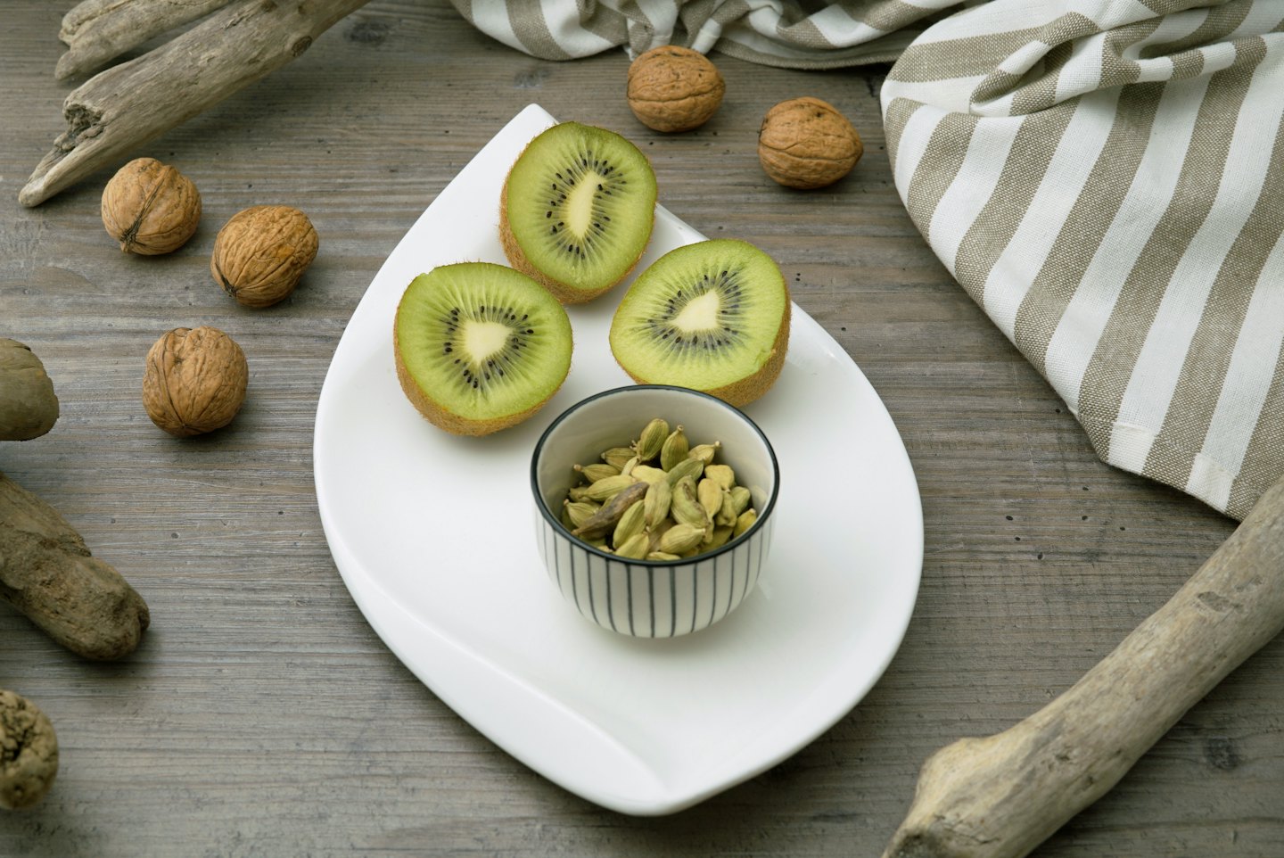 Kiwi halves and cardamom pods rest on a leaf-shaped plate.